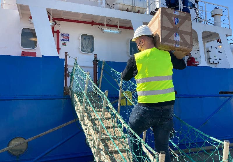 Mitarbeiter der Ems Fehn Group trägt einen Karton mit Proviant an Deck